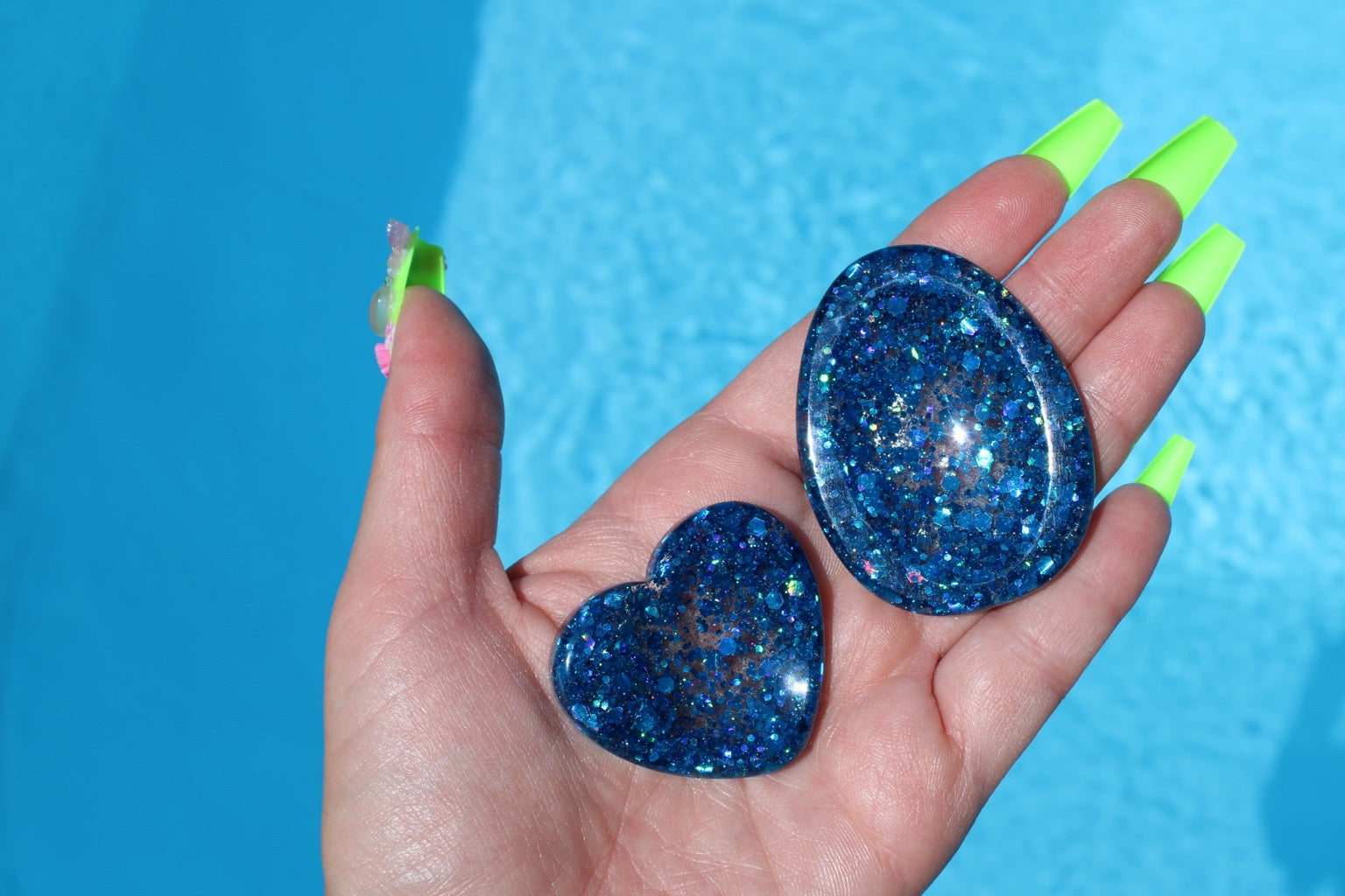 Image shows a set of 2 blue sequin anxiety tokens in front of a pool