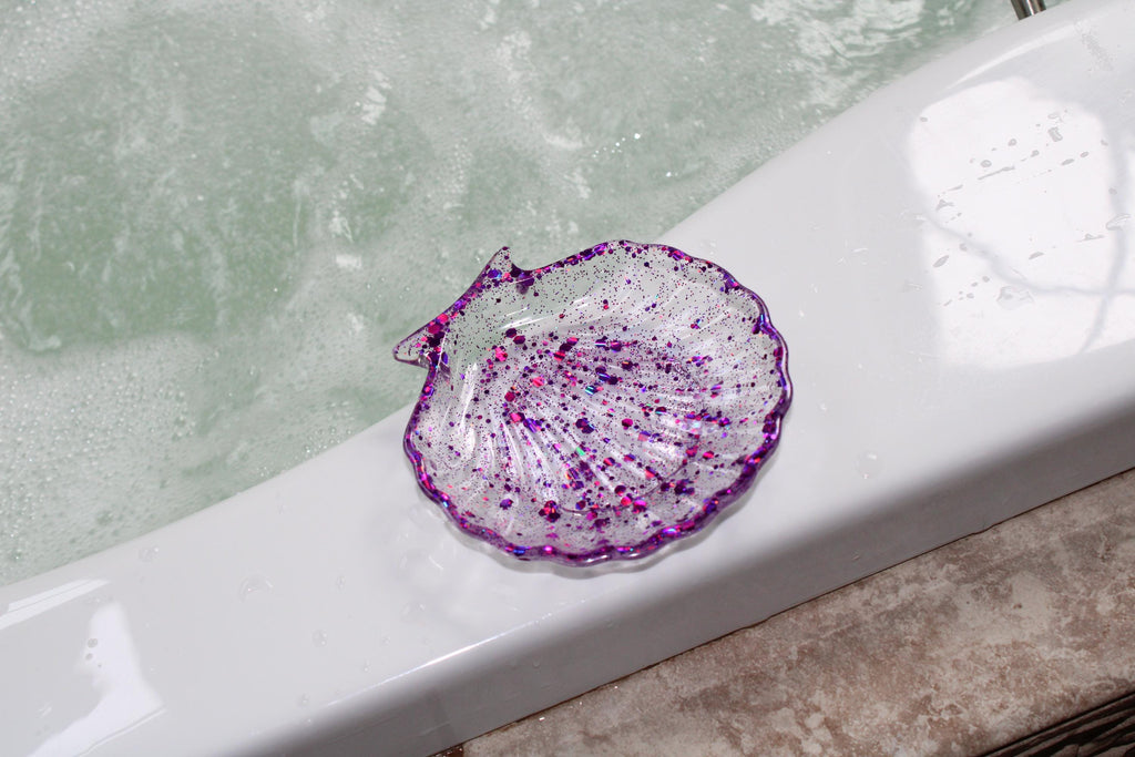 Purple sequin shell soap dish on the edge of a tub