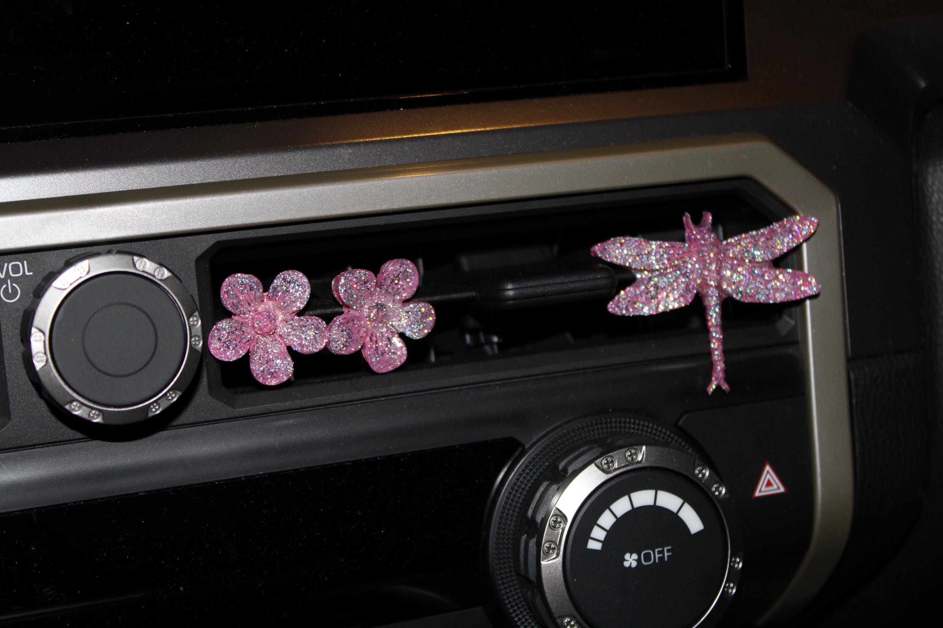 Decorative pink flowers and dragonfly on a car dashboard