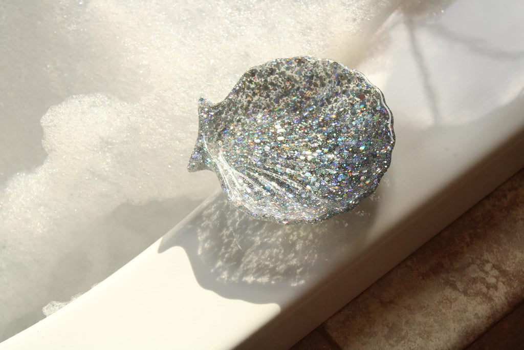 Sparkling silver shell-shaped dish on a white surface with a blurred background