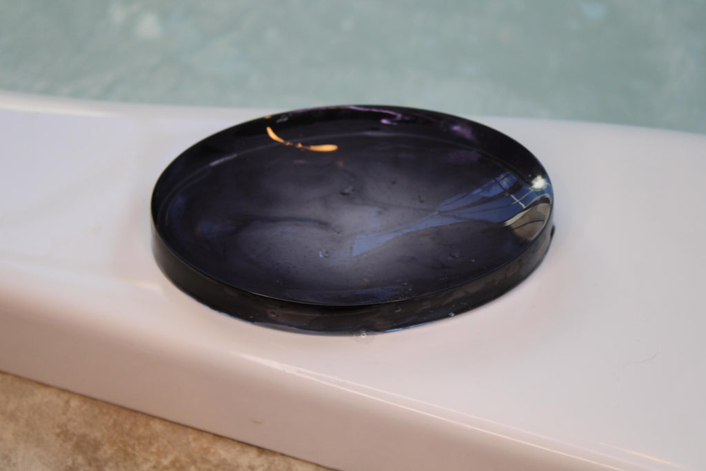 Black modern oval soap dish on a bath tub edge