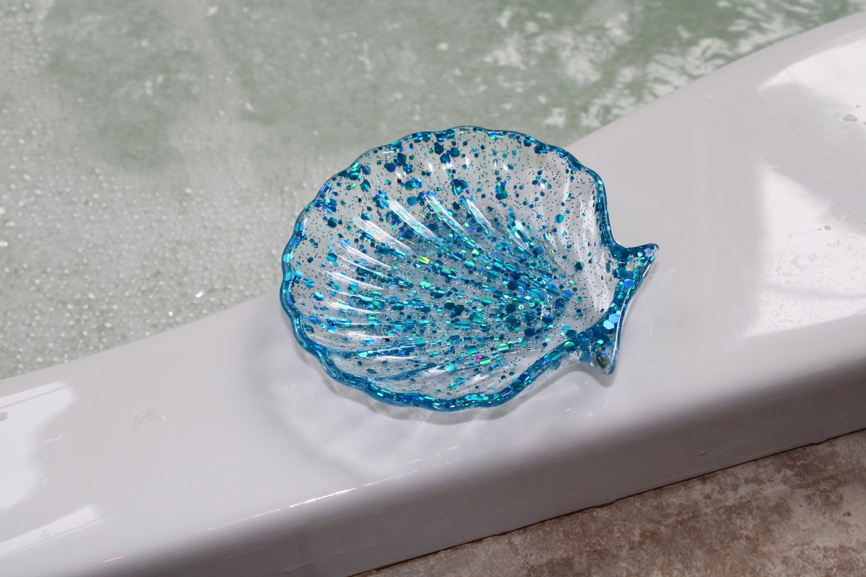 Blue glittery shell-shaped dish on a white surface with a blurred background