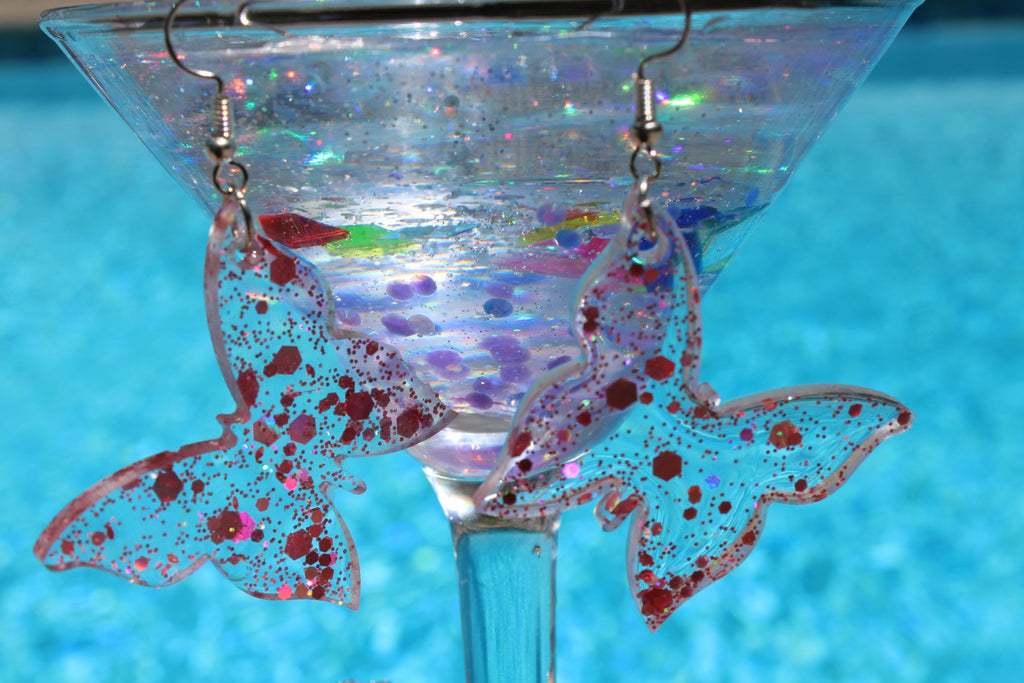 Butterfly-shaped earrings with glittery finish on a blue background