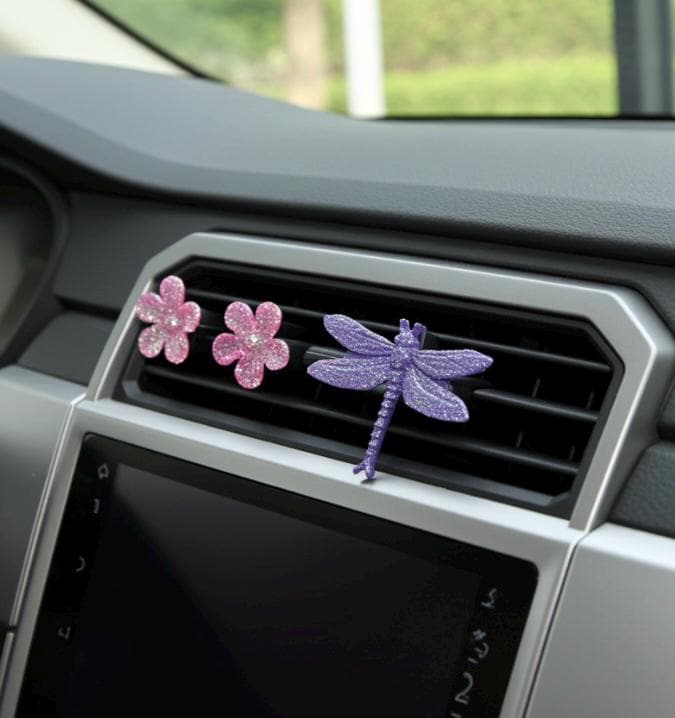 Decorative car decor with flowers and a dragonfly on a car vent.