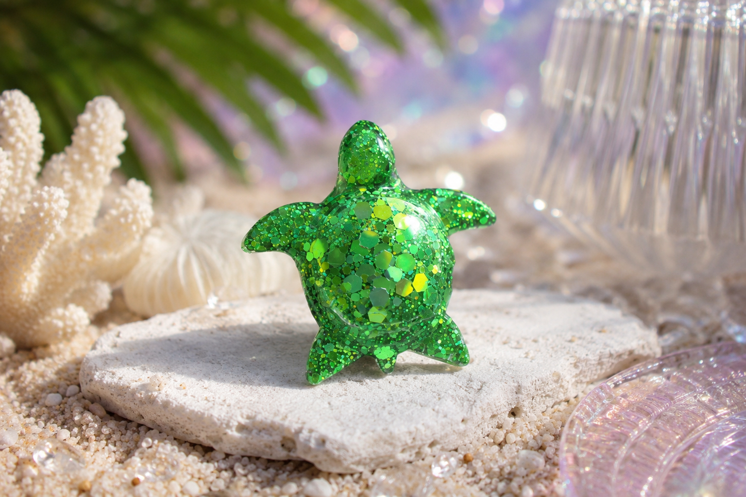 Green glittery turtle car vent clip on a sandy surface with coral and shells in the background