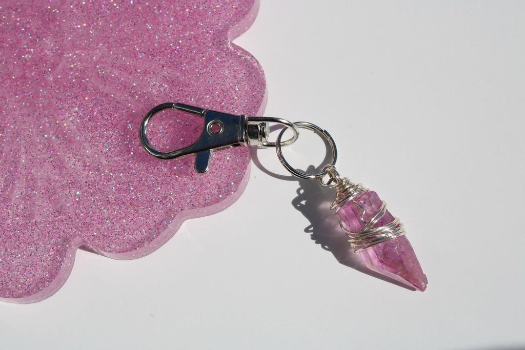 A keychain features a delicate, wire-wrapped rose quartz crystal charm.