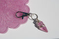 A keychain features a delicate, wire-wrapped rose quartz crystal charm.