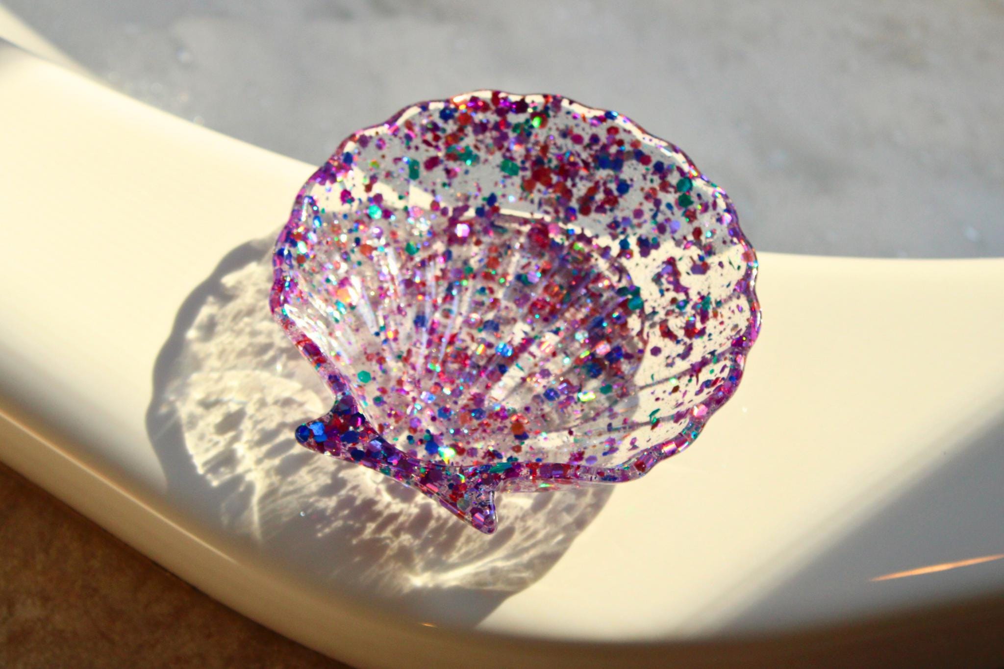 Decorative shell with colorful glitter on a white surface