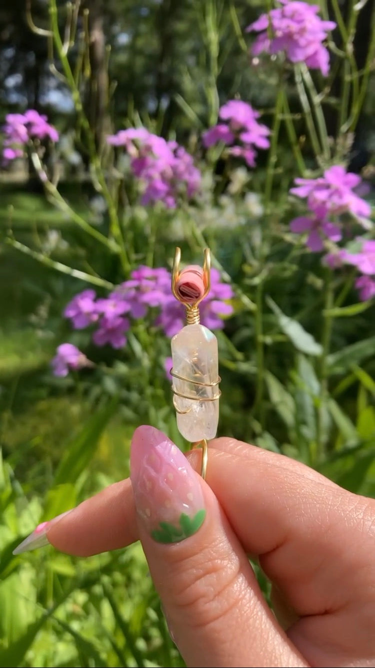 Photo shows a clear quartz crystal wire wrapped smoke ring used for smoking accessories in front of flowers 