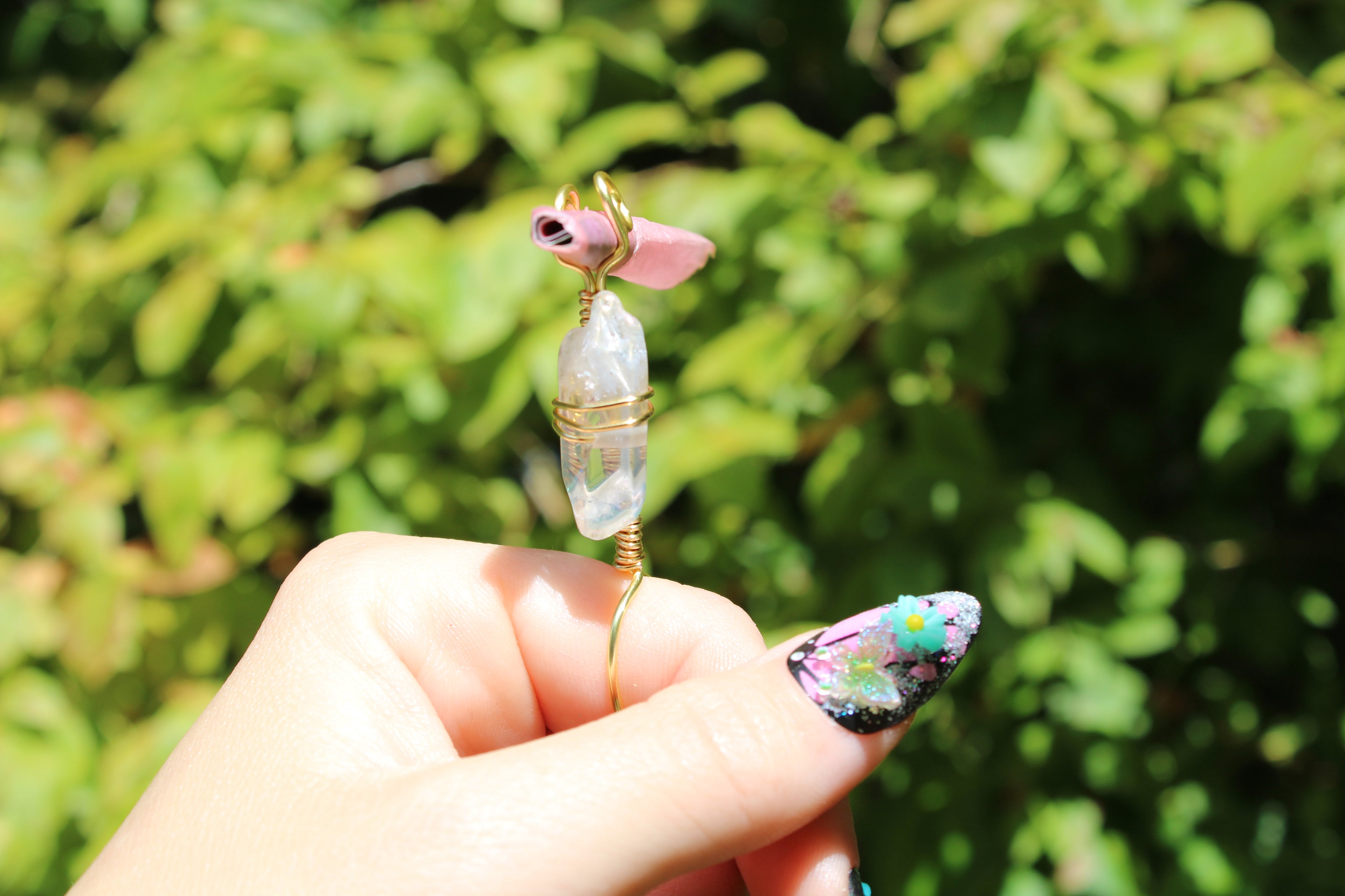Photo shows a clear quartz wire wrapped smoke ring in front of a bush