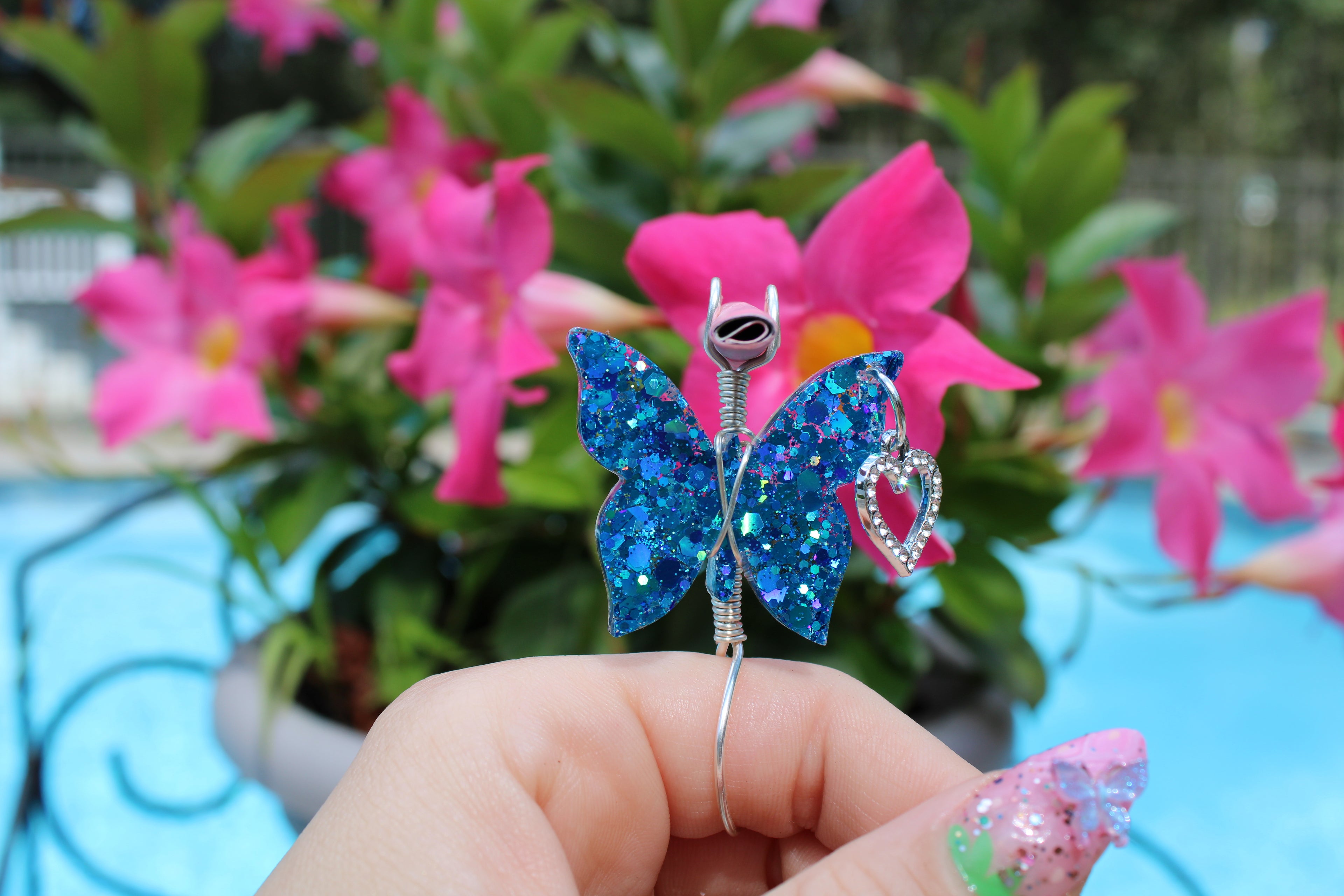 Blue Sequin Butterfly Smoke Ring With Faux Joint In Front Of A Flower
