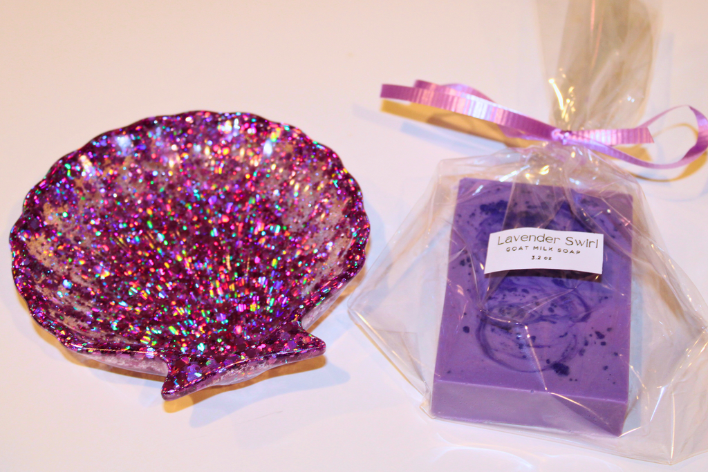 Sparkling seashell trinket dish sits next to a wrapped bar of Lavender Swirl goat milk soap.