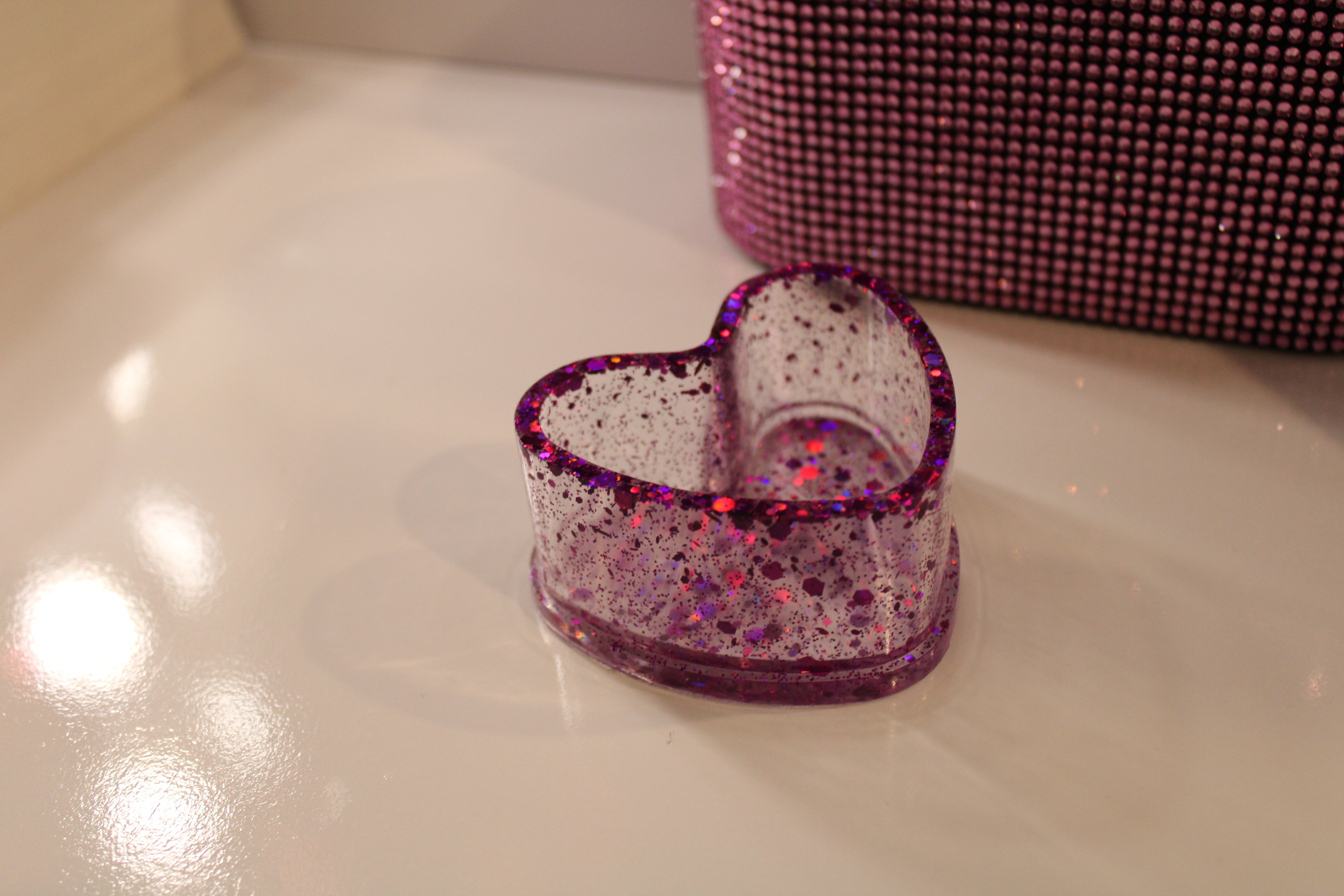 Heart-shaped glittery ring dish on a vanity