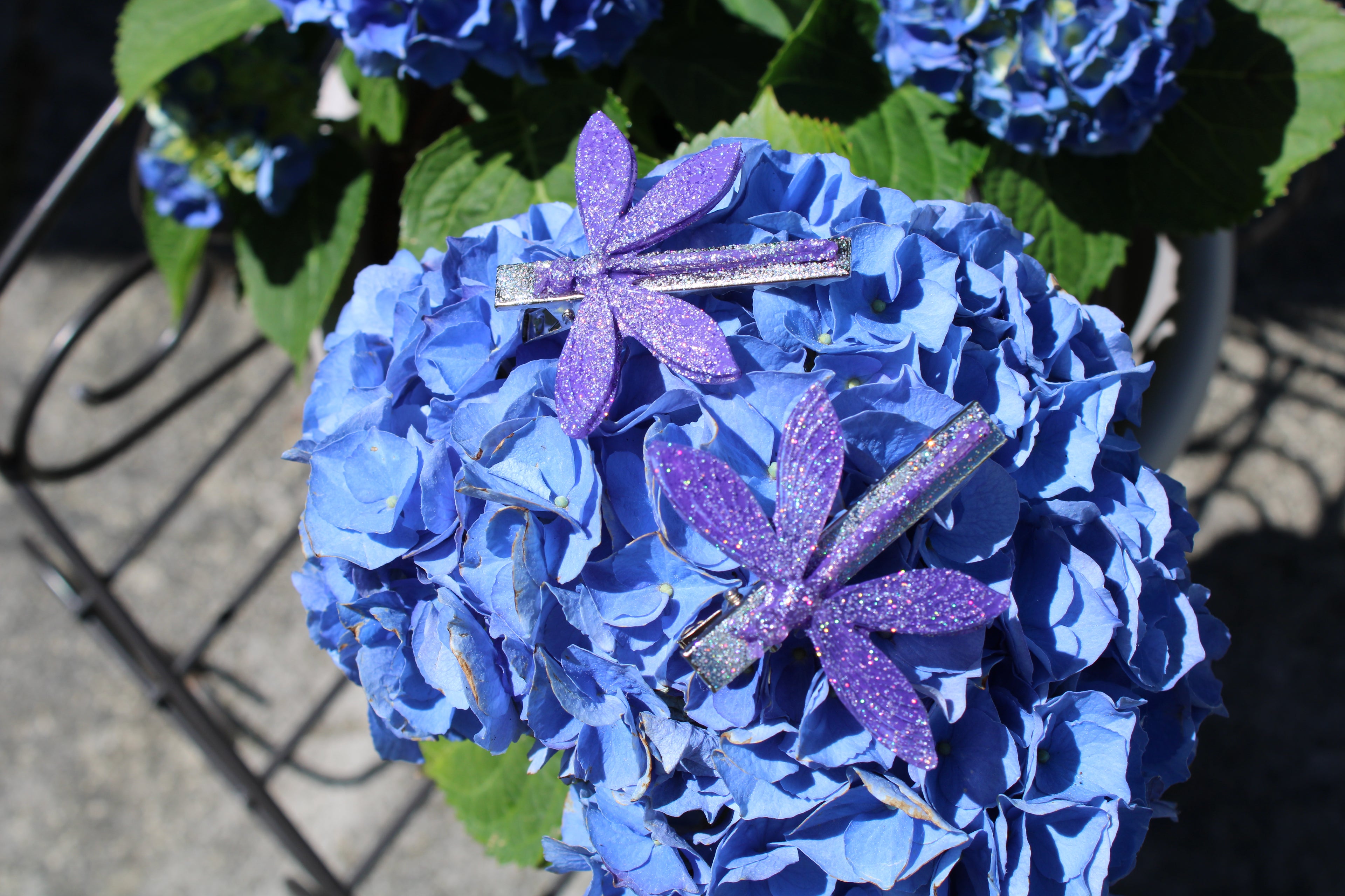 Blue hydrangea flower with decorative purple dragonfly hair clips on a blurred background