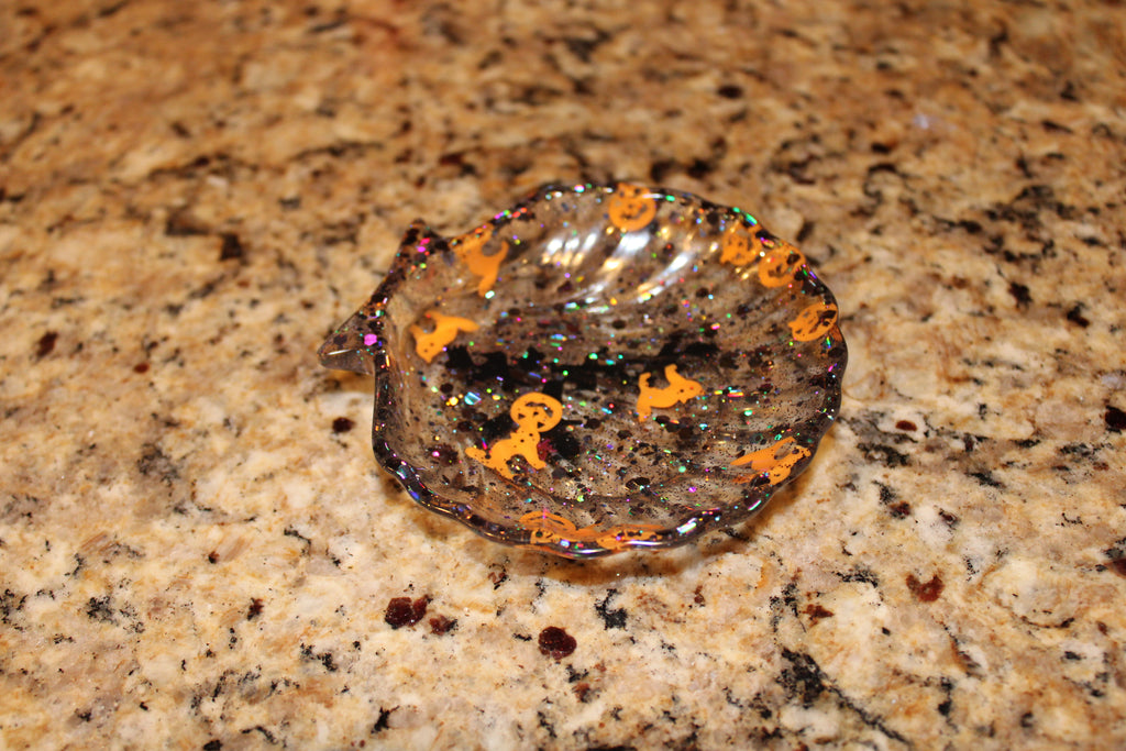 Resin artist crafts a sparkly, seashell-shaped Halloween candy dish with pumpkin and ghost decorations.