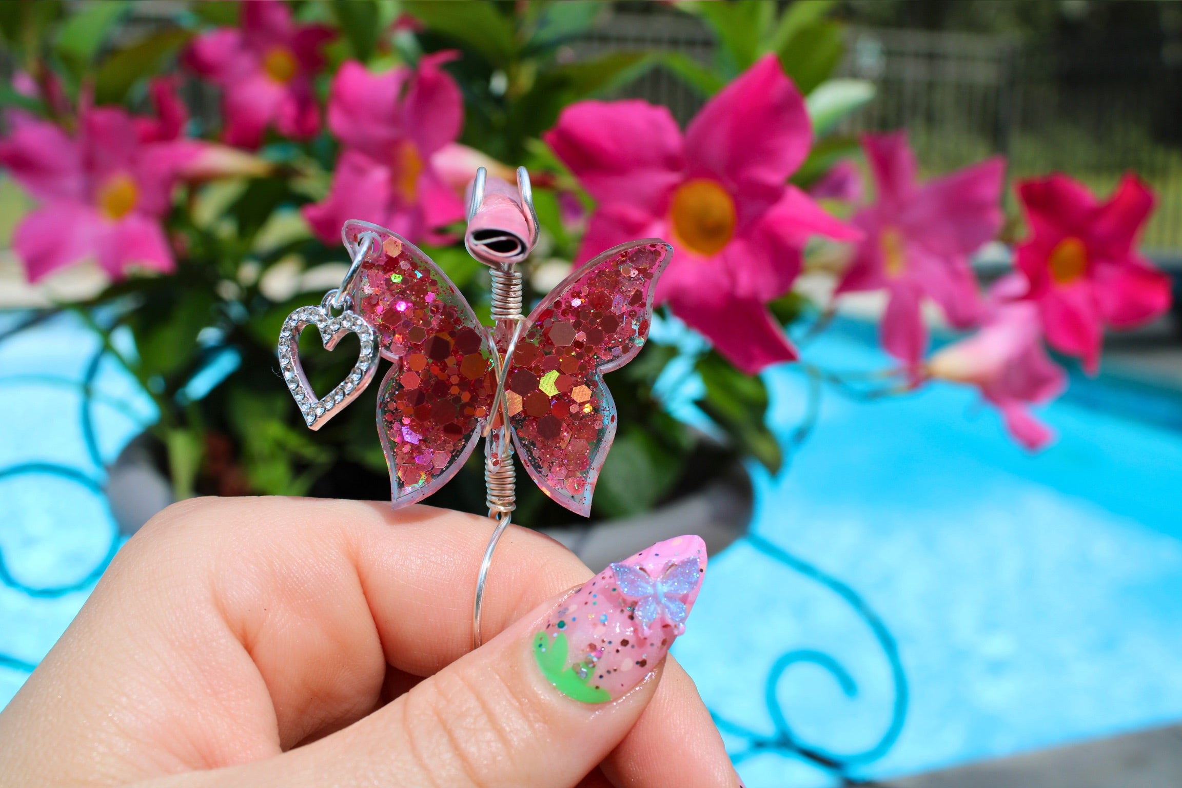 Pink sequin butterfly smoke ring in front of a plant 