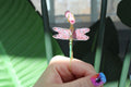 Hand holding a decorative dragonfly smoke ring with pink and gold details.