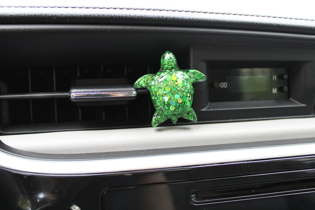 Green turtle-shaped car vent clip on a car dashboard