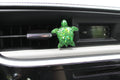 Green turtle-shaped car vent clip on a car dashboard