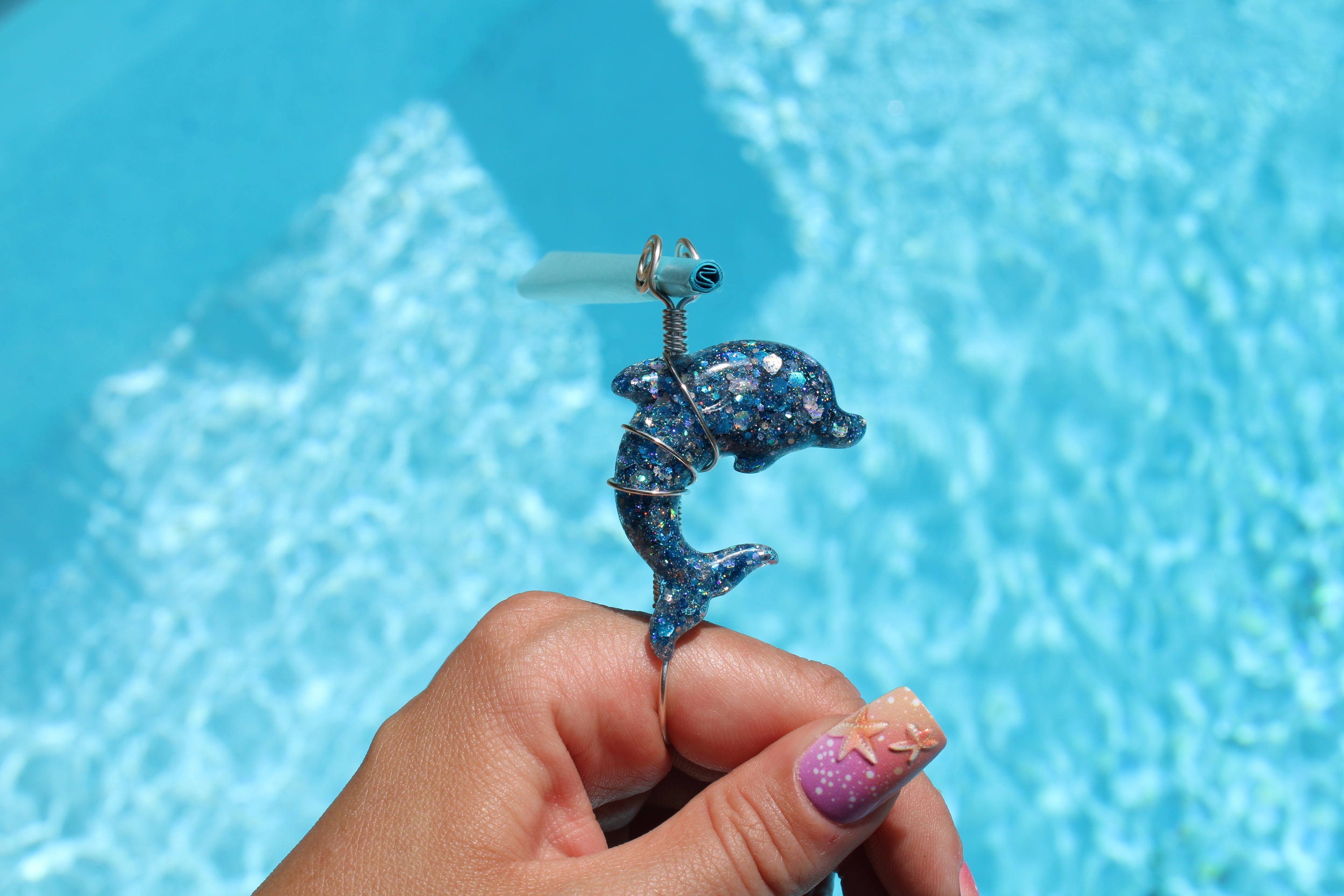 Dolphin smoke ring held by a hand with a blue water background