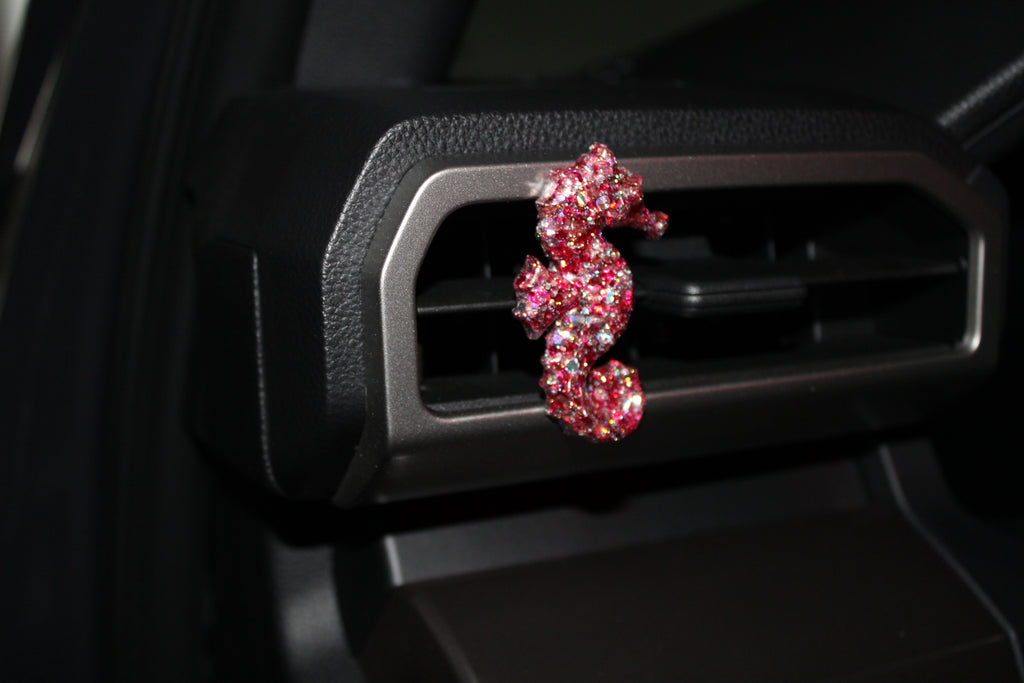 Pink seahorse-shaped car vent clip on a car's air vent.