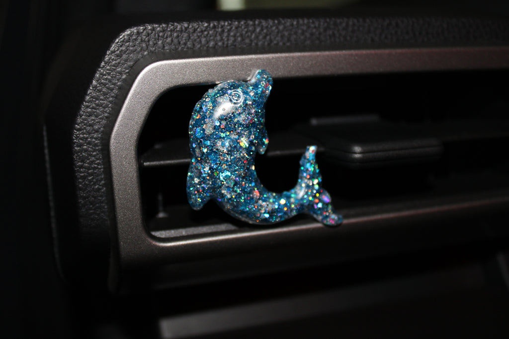 Decorative blue glittery dolphin in a car's air vent.