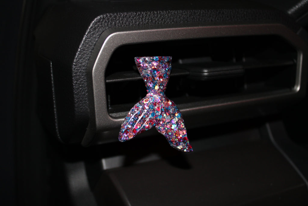 Multicolored car vent clip shaped like a mermaid tail on a car vent.