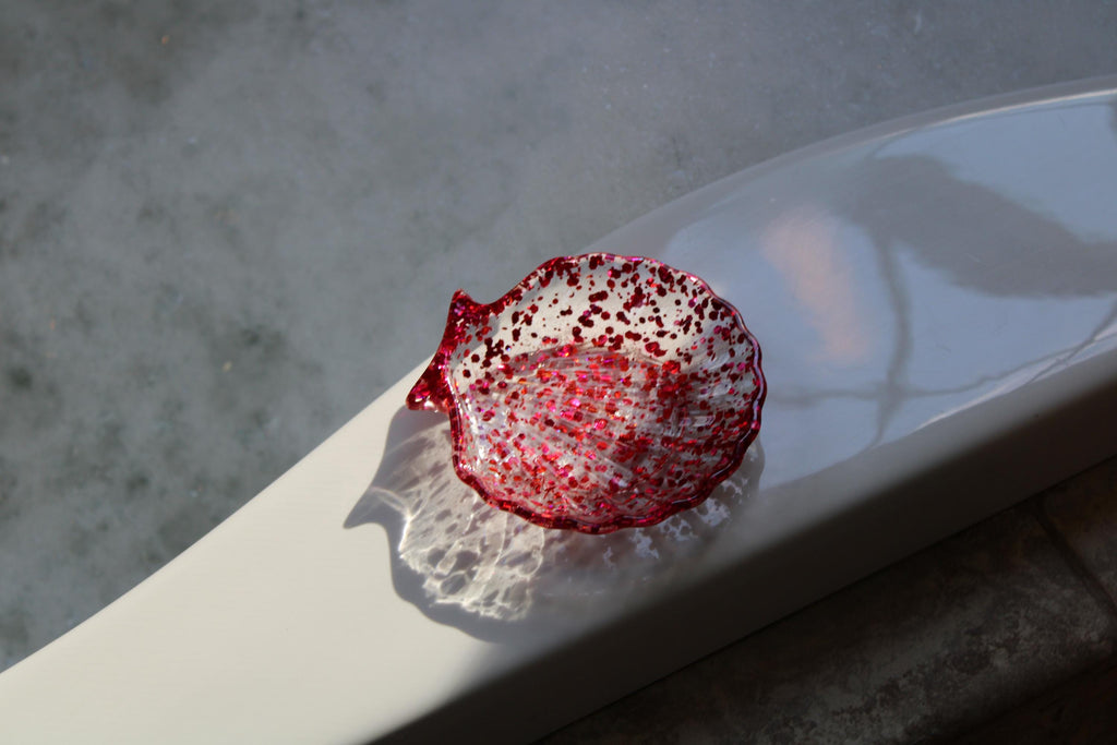 Rose pink seashell soap dish on the edge of a tub