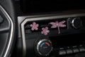 Decorative car decor shaped like flowers and a dragonfly on a car dashboard.