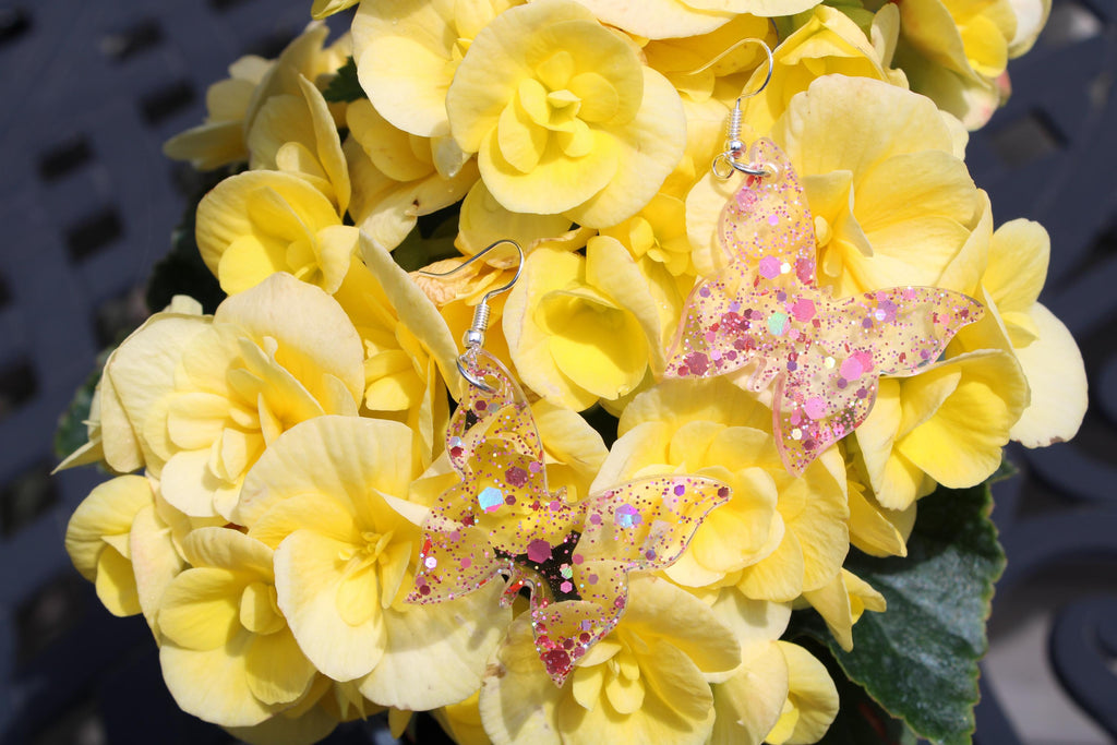 Yellow flowers with decorative butterfly earrings on a blurred background
