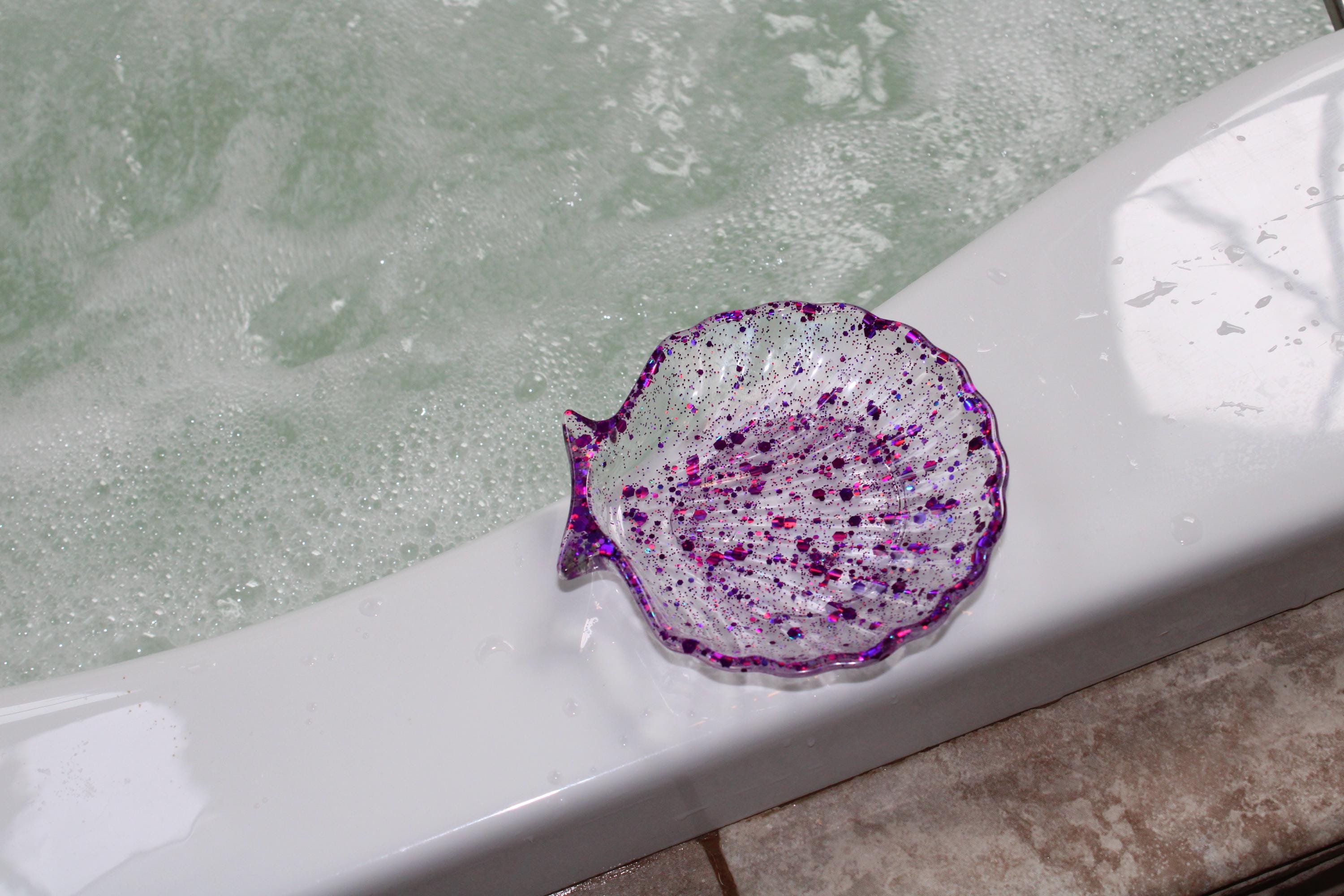 Decorative purple shell-shaped soap dish on a bathtub with water
