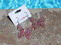 Butterfly earrings on a card with a pool in the background