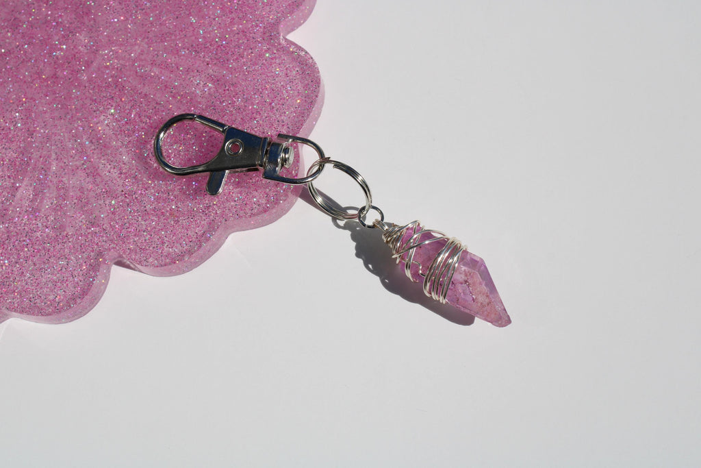 A sparkly pink resin tray displays a handmade pink crystal point keychain wrapped with silver wire.