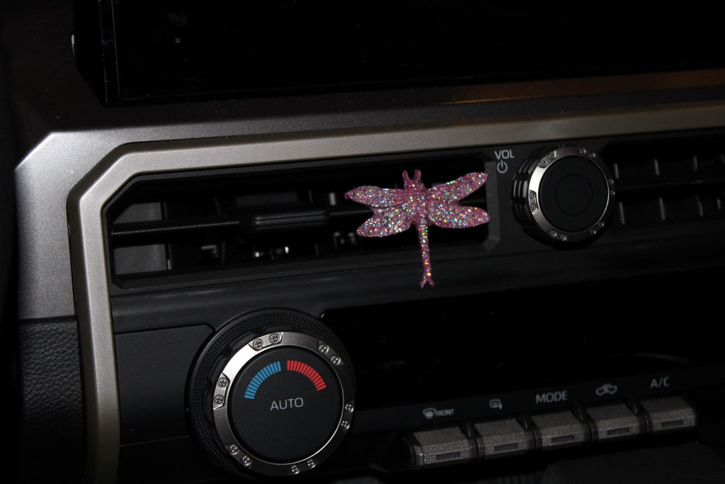 Car air vent with decorative pink dragonfly and control knobs