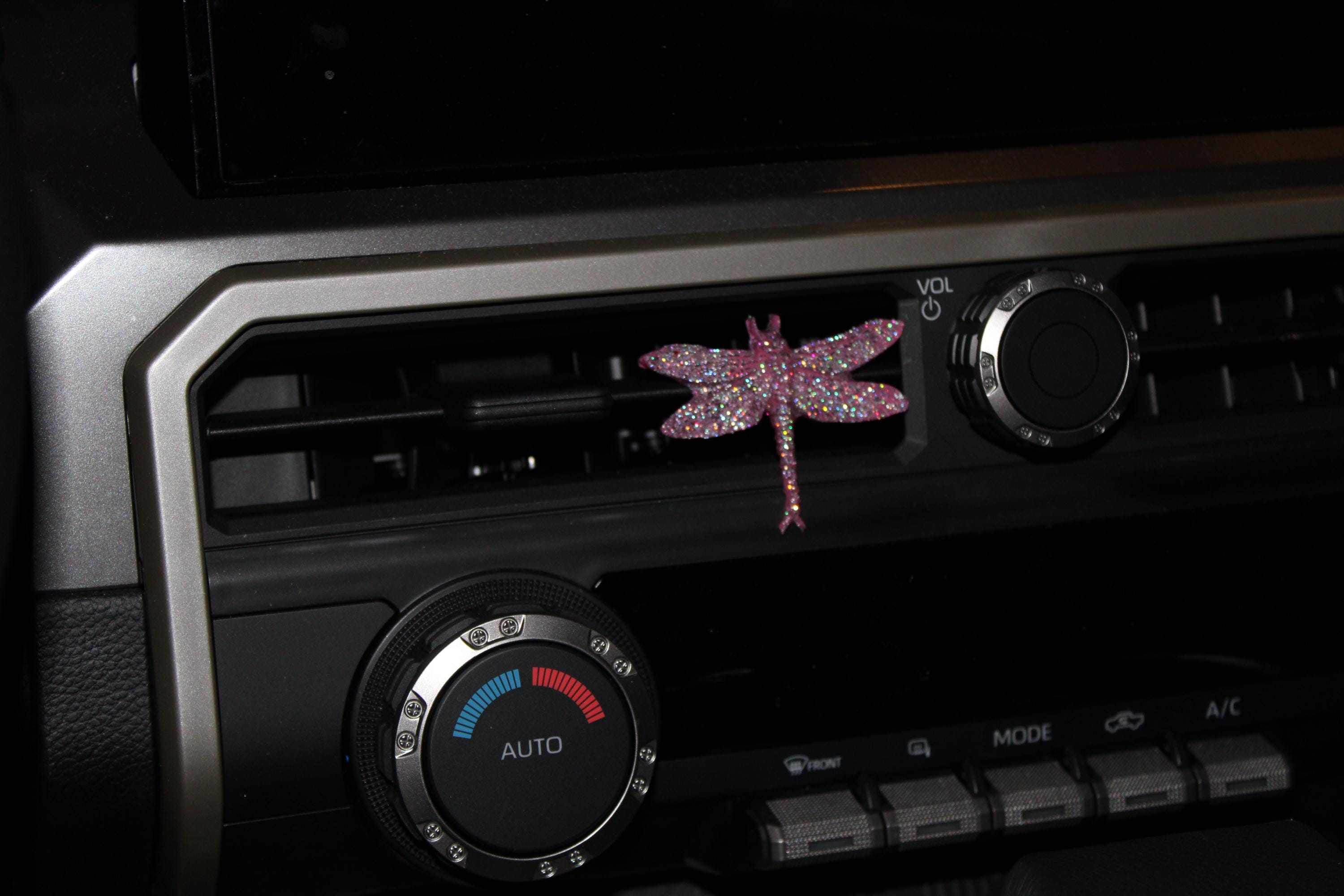 Car air vent with decorative pink dragonfly and control knobs