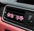 Pink flower-shaped car decor on a car's air vent.
