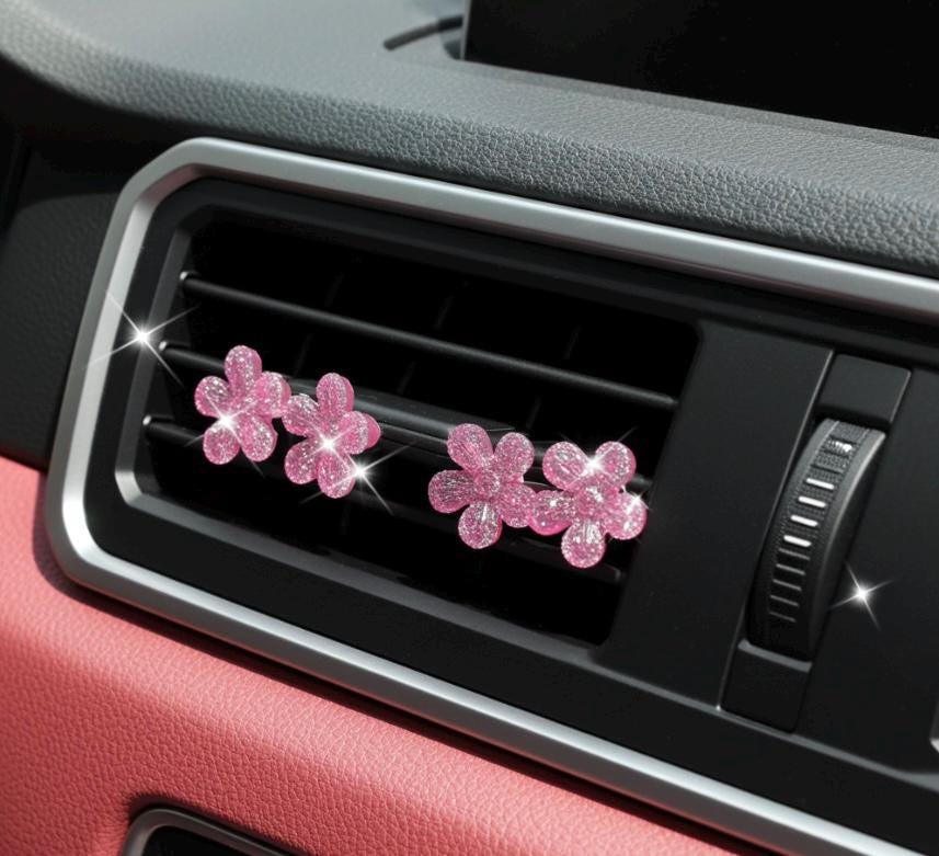 Pink flower-shaped car decor on a car's air vent.