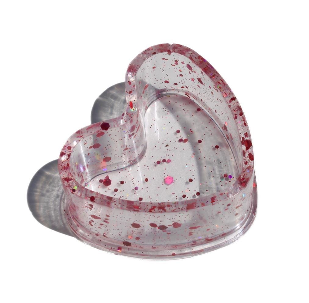 Clear heart-shaped dish with pink speckles on a white background