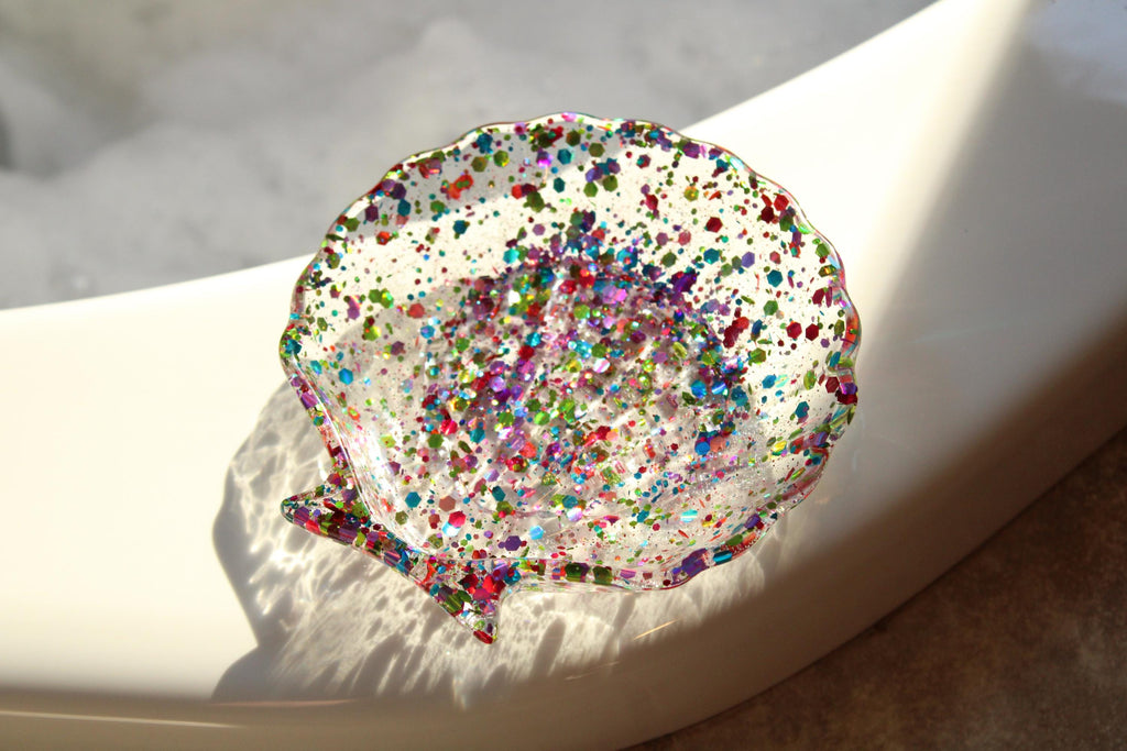 Shell-shaped dish with colorful speckles on a white surface