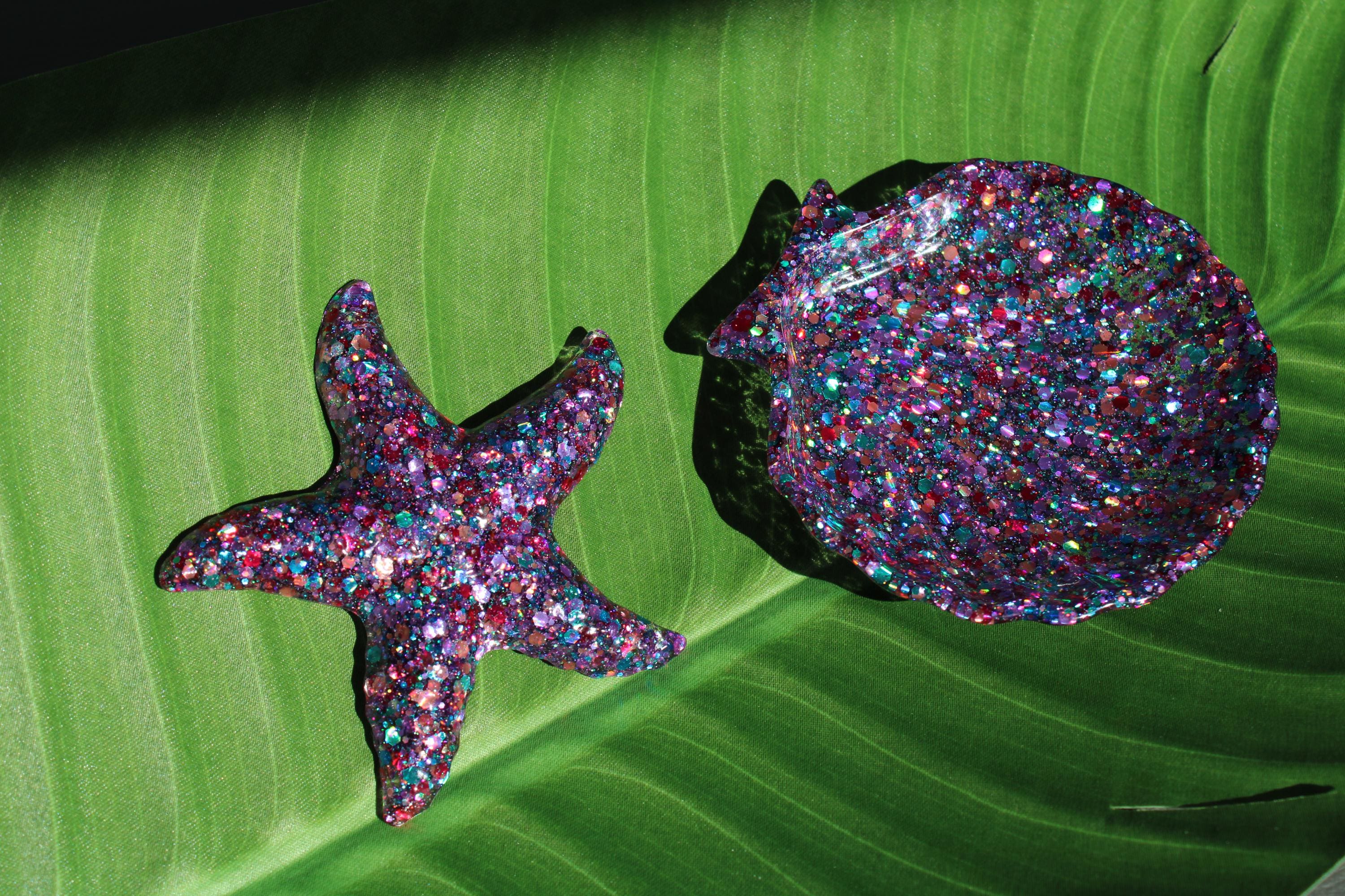 Glittery starfish and shell on a green leaf