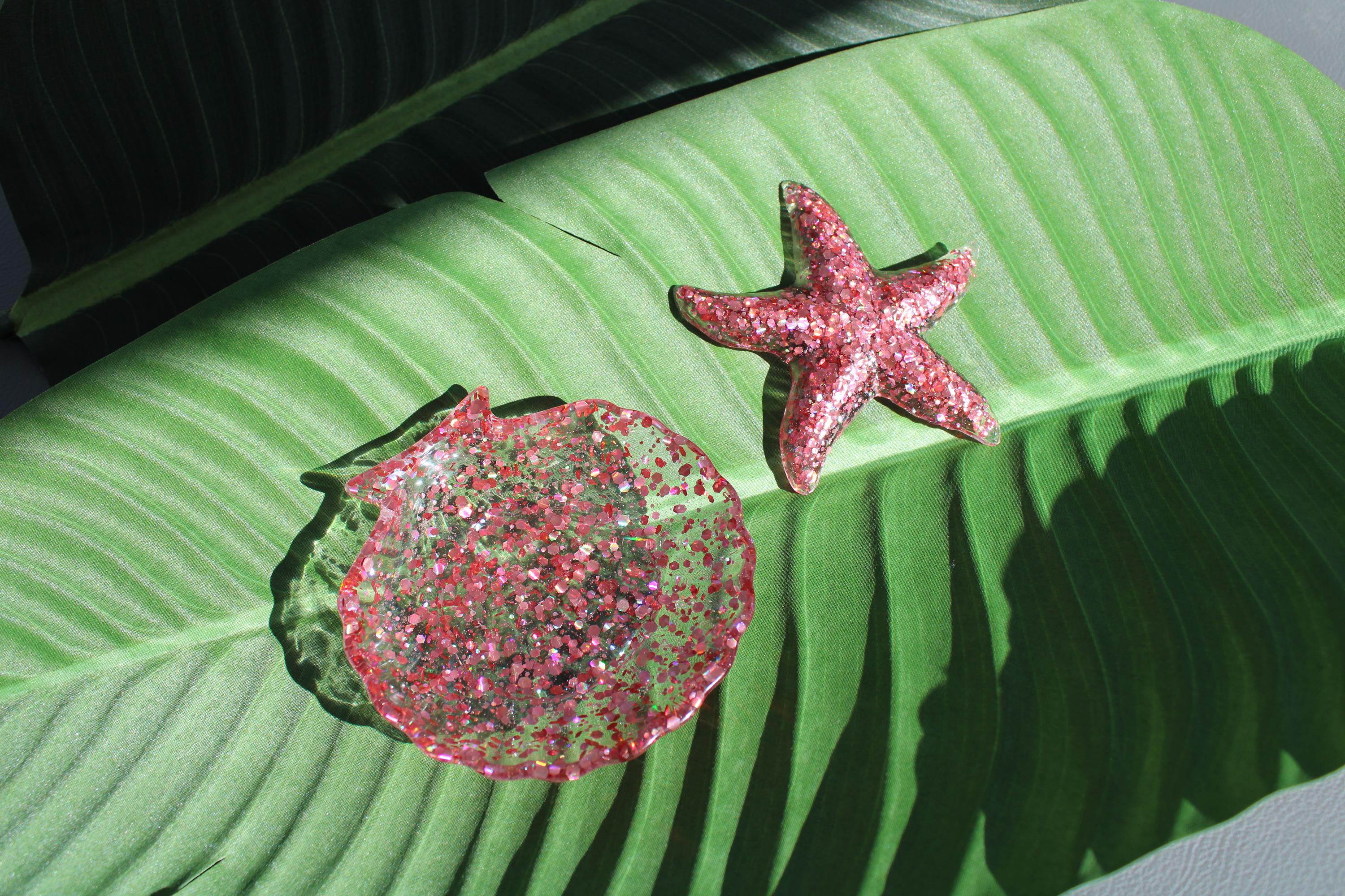 Pink glittery starfish and seashell dish on a green leaf