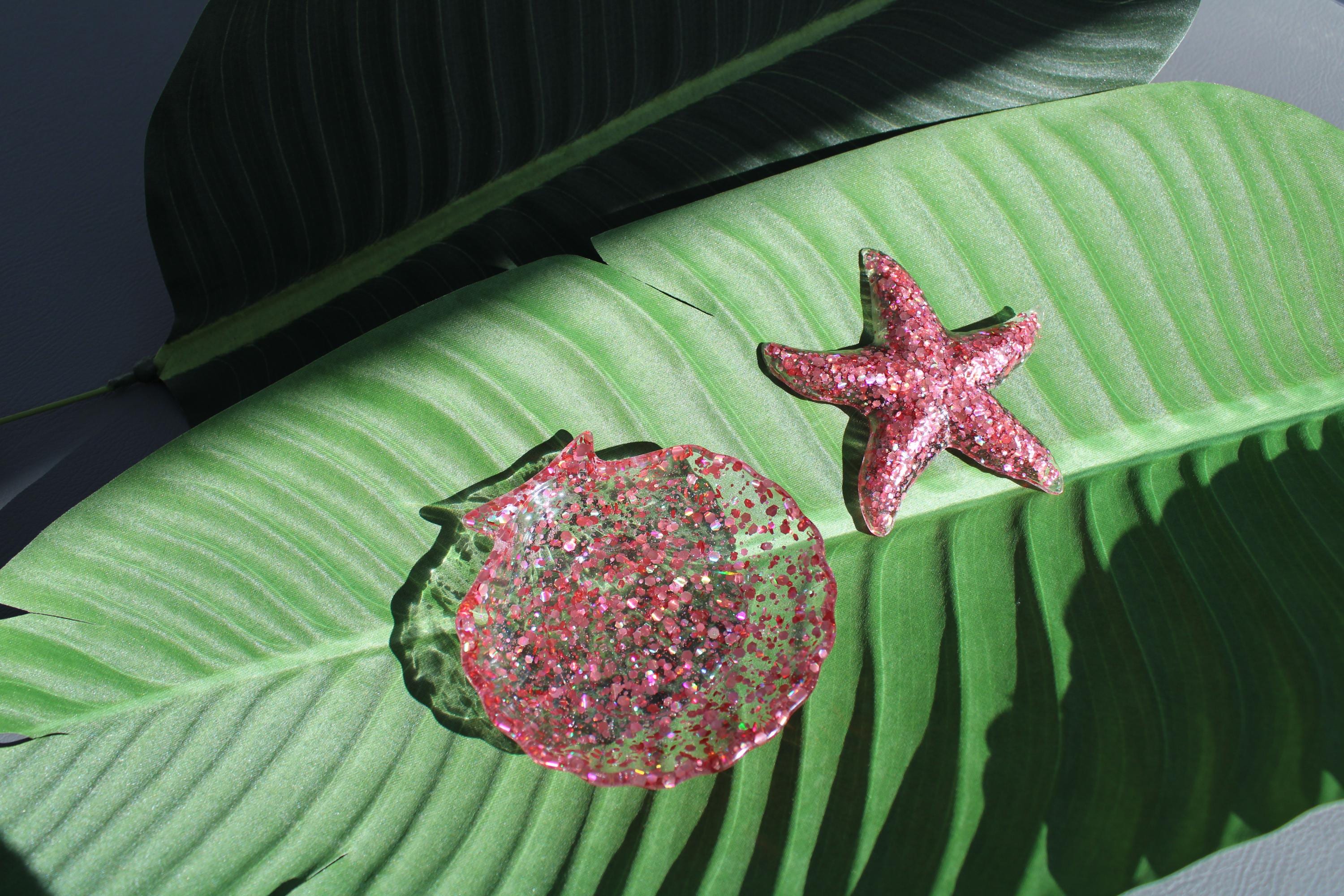 Pink glittery starfish and seashell dish on a green leaf