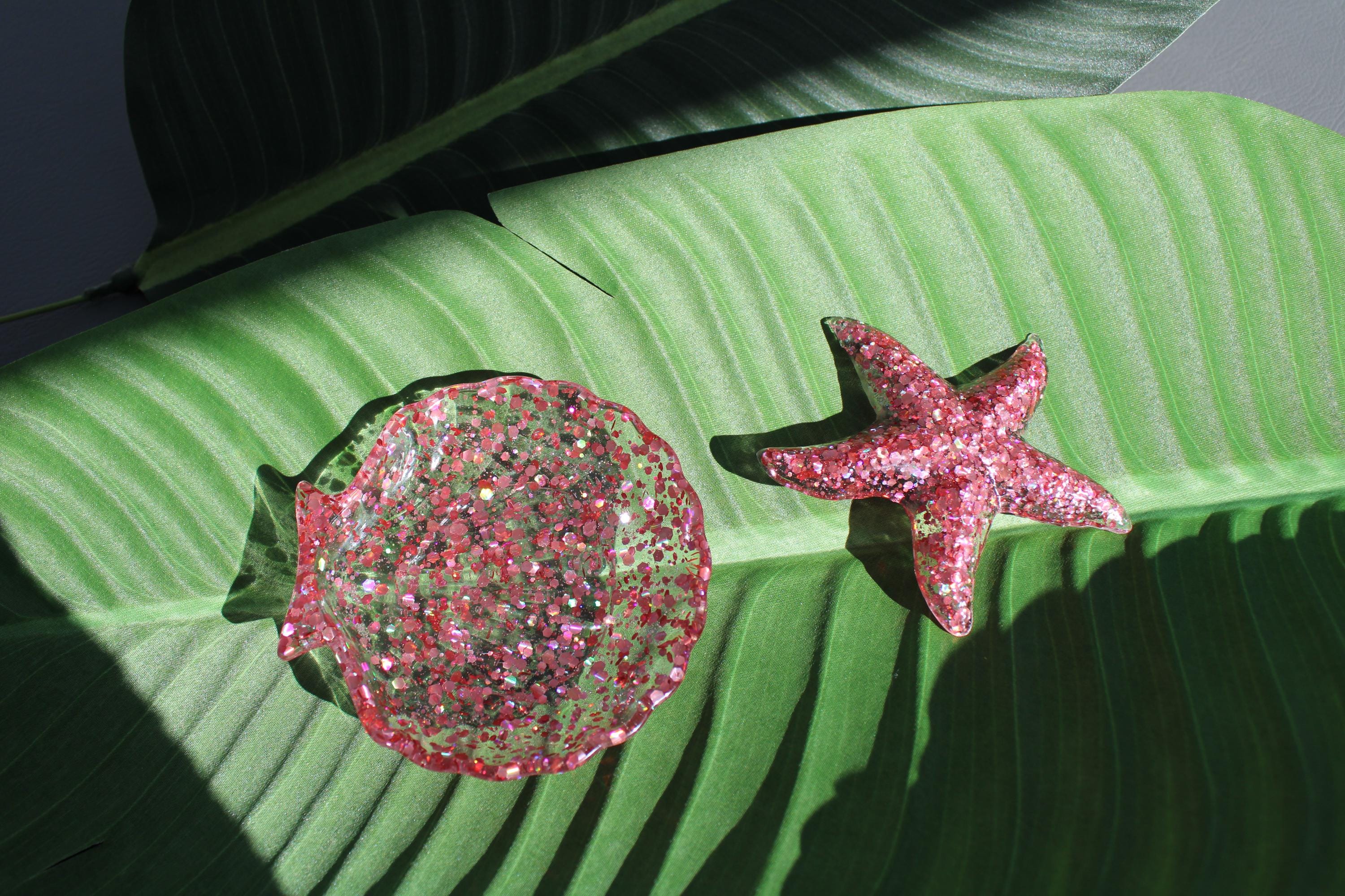 Pink glittery seashell and starfish decor on a green leaf
