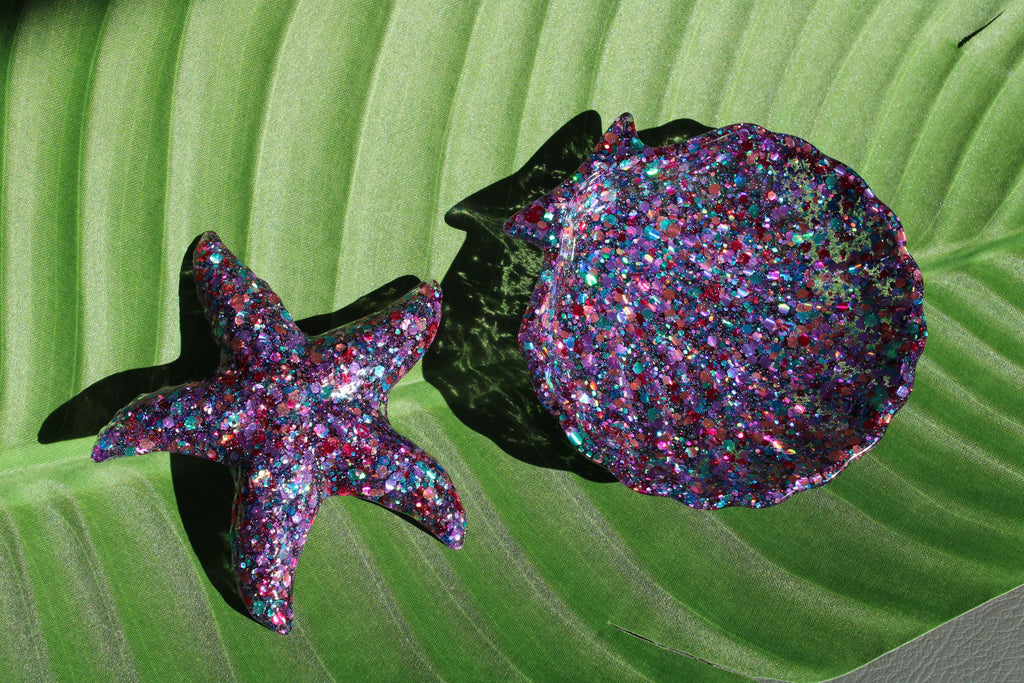 Glittery starfish and shell on a green leaf background