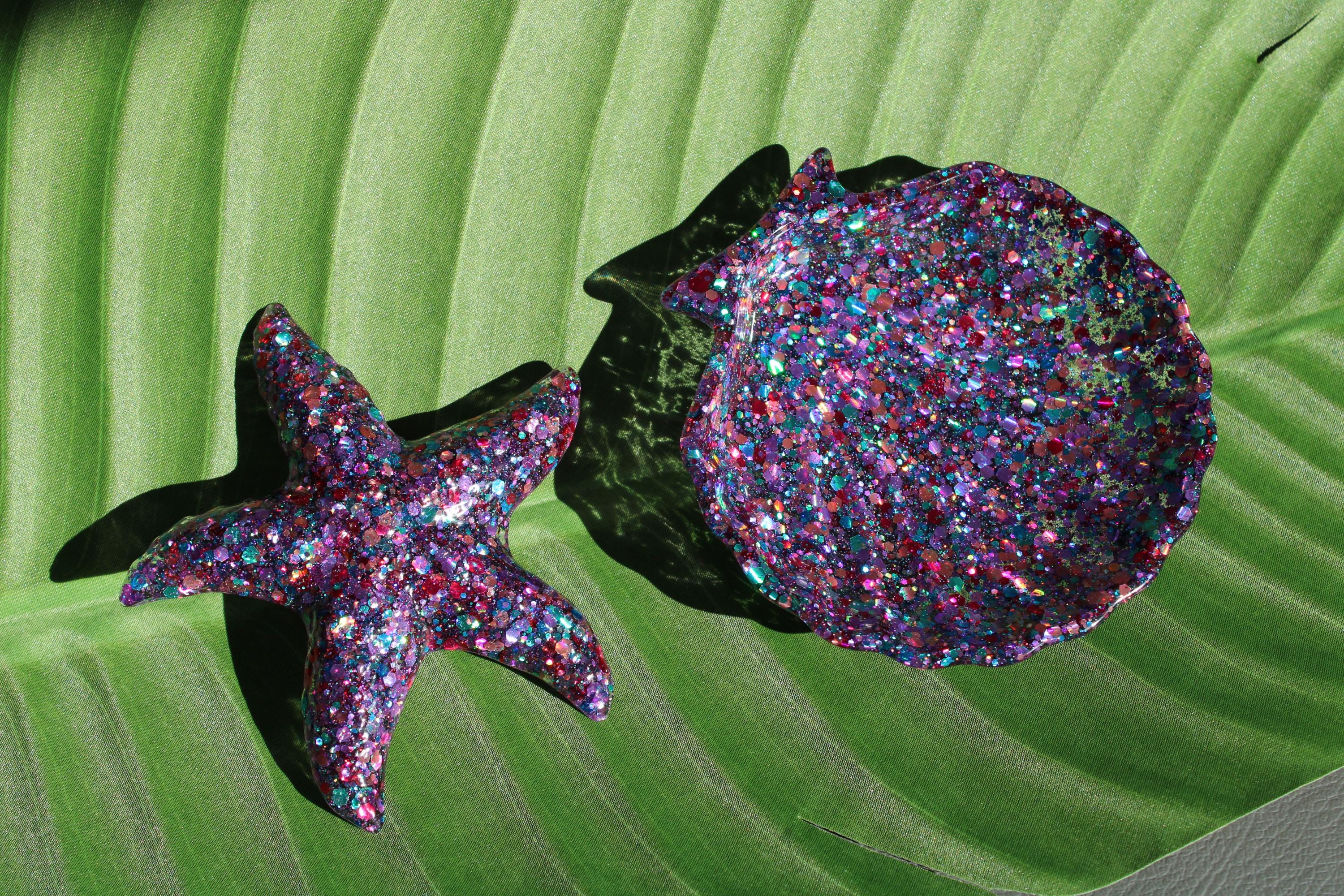 Glittery starfish and shell on a green leaf background