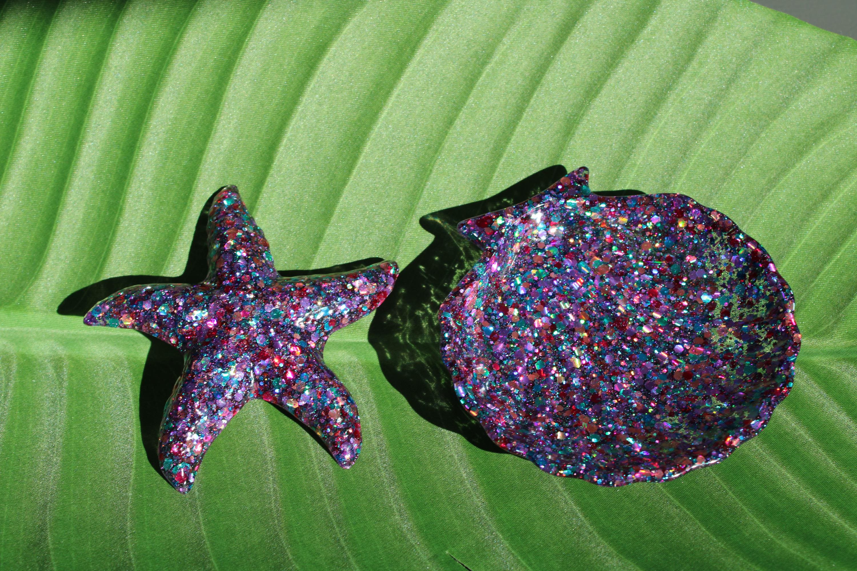 Glittery starfish and seashell dish on a green leaf background