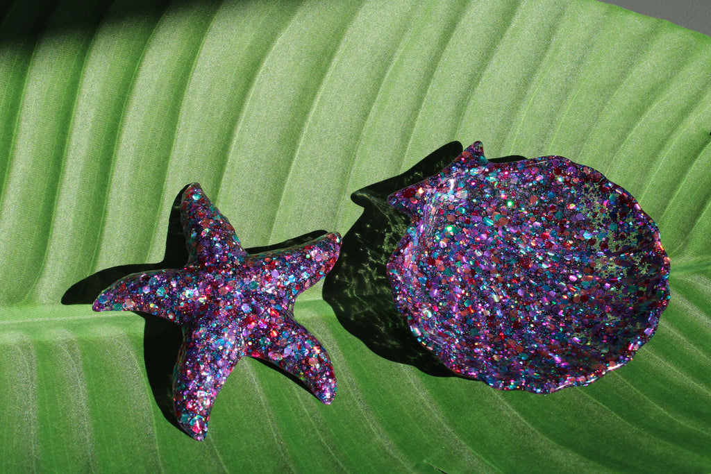 Glittery starfish and shell on a green leaf background