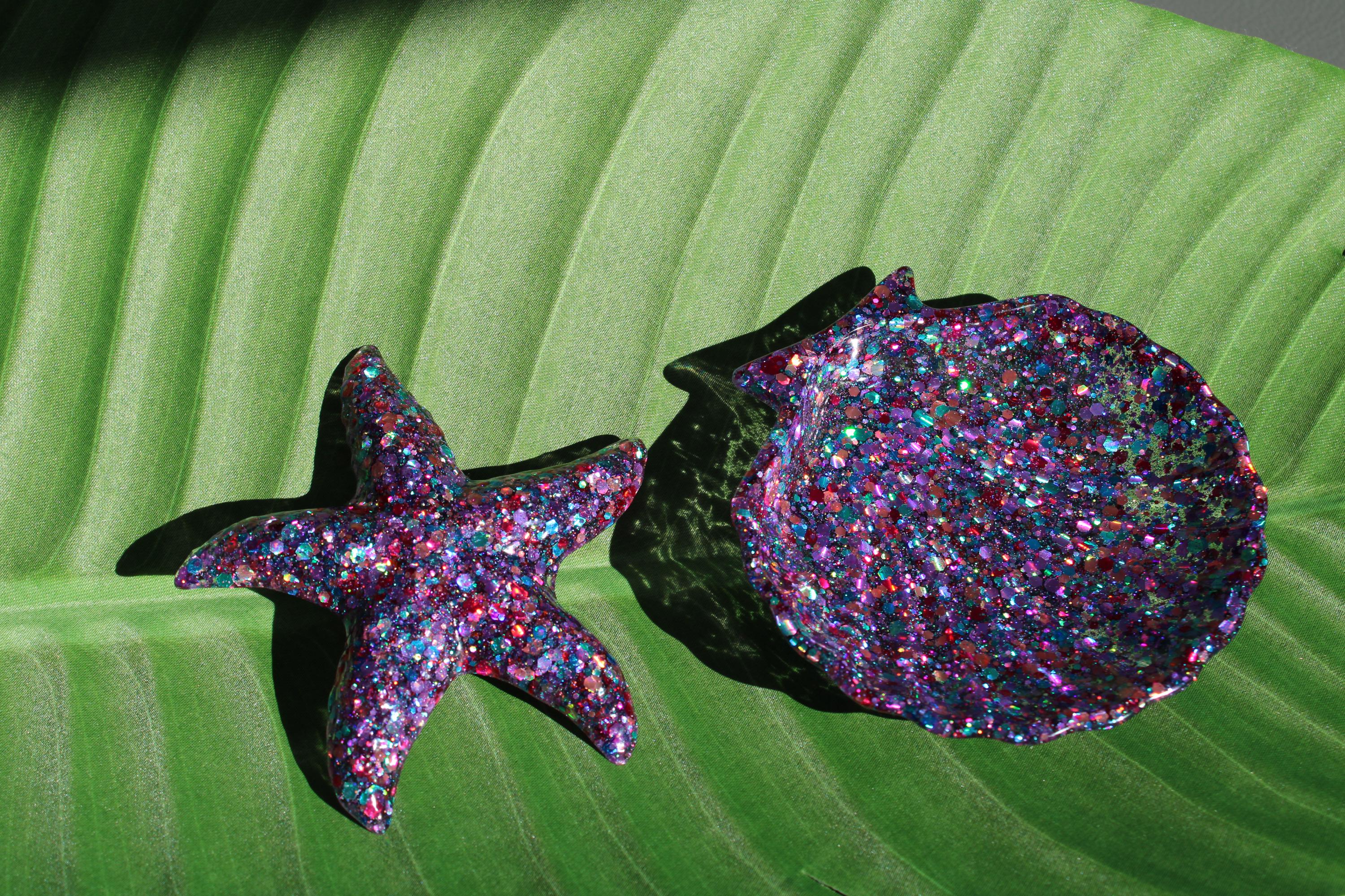 Glittery starfish and shell on a green leaf background