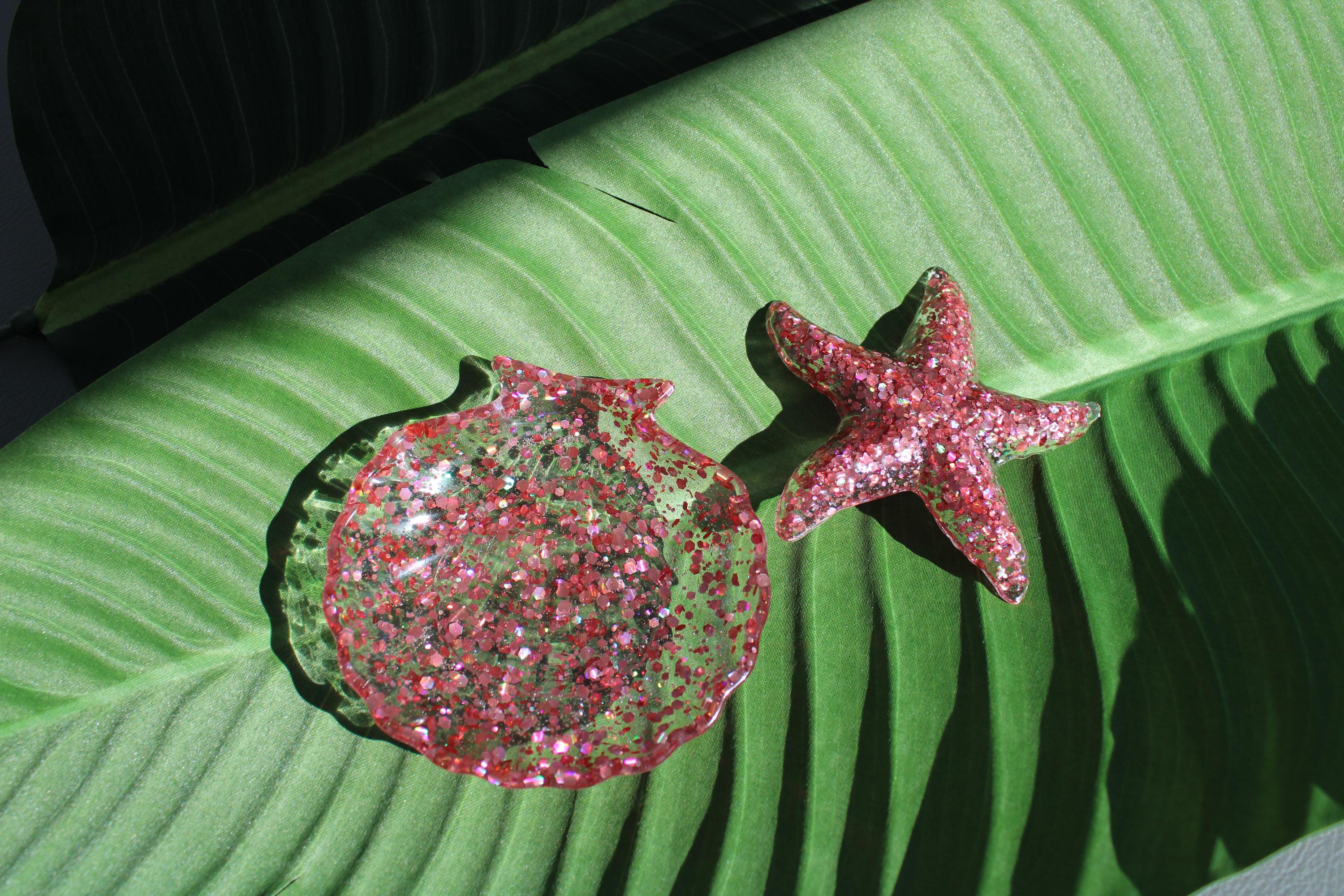 Pink glittery shell and starfish on a green leaf