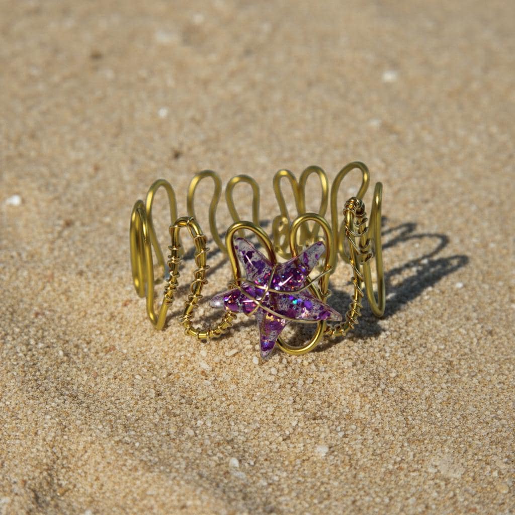 Gold bracelet with a purple starfish charm on sandy ground